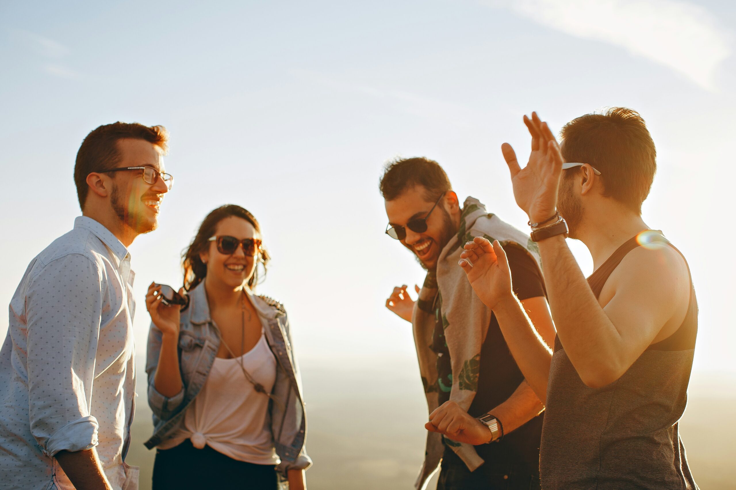 Three men and one woman laughing outdoors